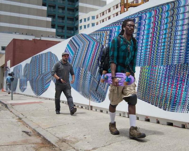 Two people walk by a mural consisting of overlapping circles of various colors