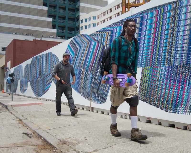 Two people walk by a mural consisting of overlapping circles of various colors