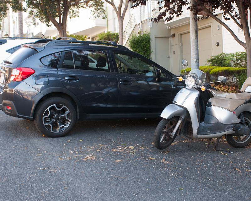 car and moped parked on street