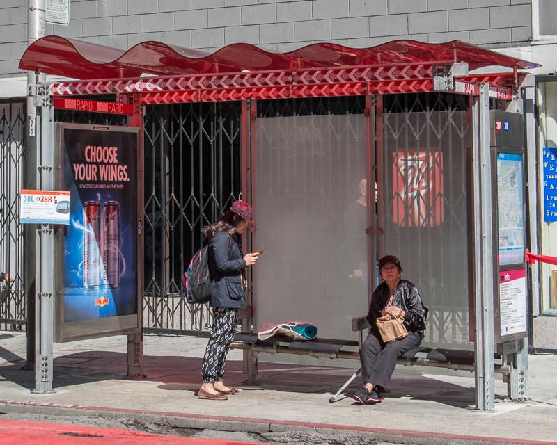 people waiting for bus inside Muni bus shelter