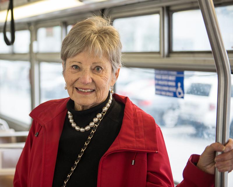 senior citizen woman holding onto stanchion inside Muni bus