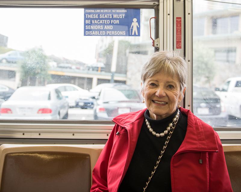 older woman sitting in front seating on Muni bus.