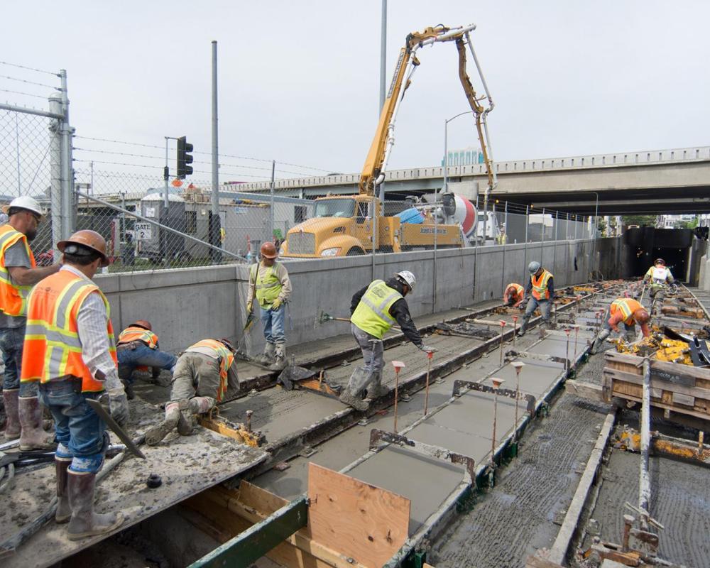 Workers traverse the site carefully during the last of the tunnel portal invert concrete pour, completing the foundation and roa