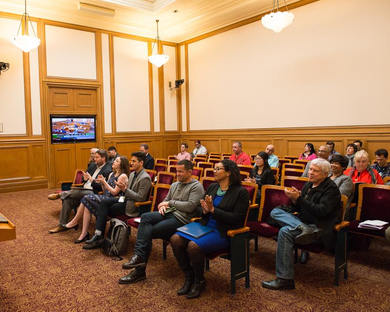 group of people sitting in large room inside city hall