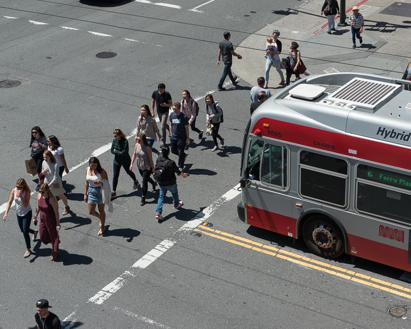 people crossing street in front of muni bus