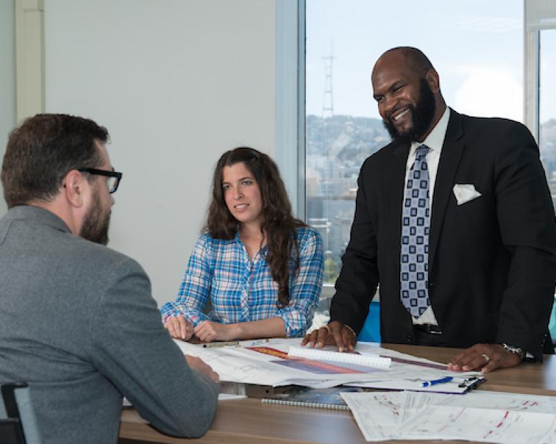 Three SFMTA staff collaborating with Sutro tower in the distance