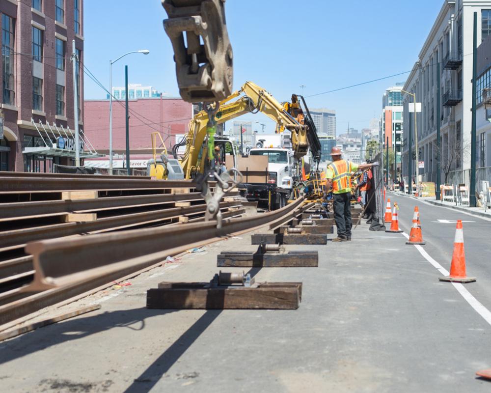 Another length of rail is lifted into place onto steel rollers to be moved north up 4th Street.