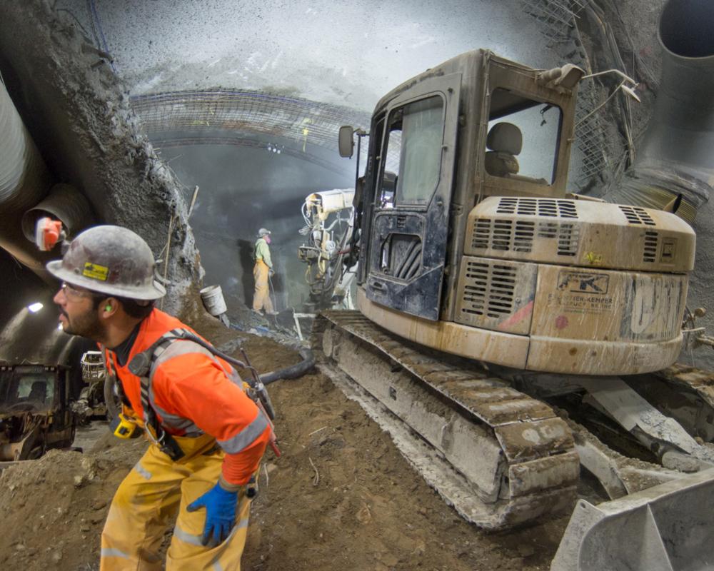 Workers use a shotcrete spraying machine inside the top header of the north platform cavern of Chinatown Station.