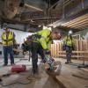 Carpenters cut boards to build cross-bracing as part of concrete form construction at the south headwall of the UMS station box.