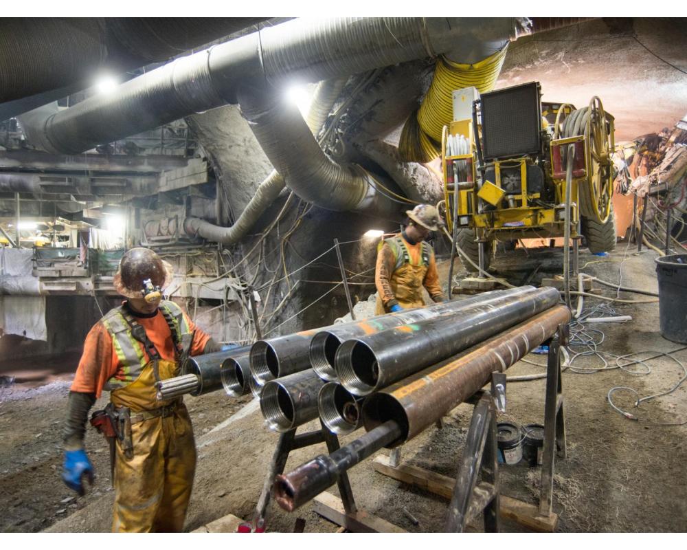 Two men ready a section of drill casing before lifting it up the ramp to the drill rig positioned as part of grouting work for t