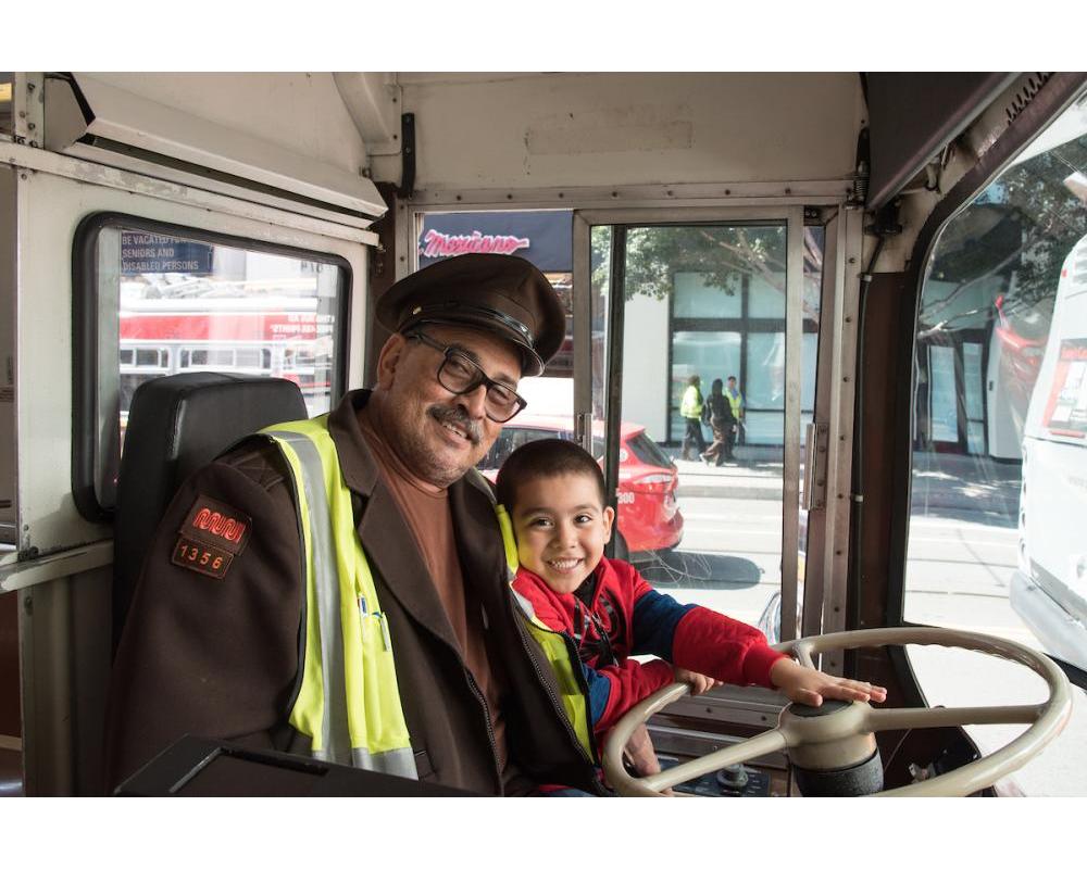 An operator and his son sit on a historic bus