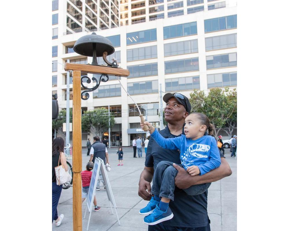 Child rings a bell at community event.