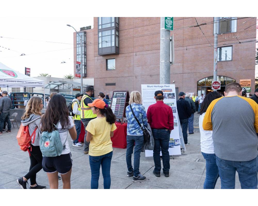 Small group of community members learn about the SFMTA at community event.