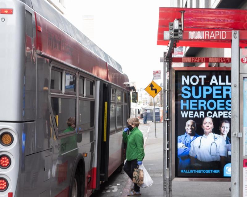 A person boards Muni wearing a mask