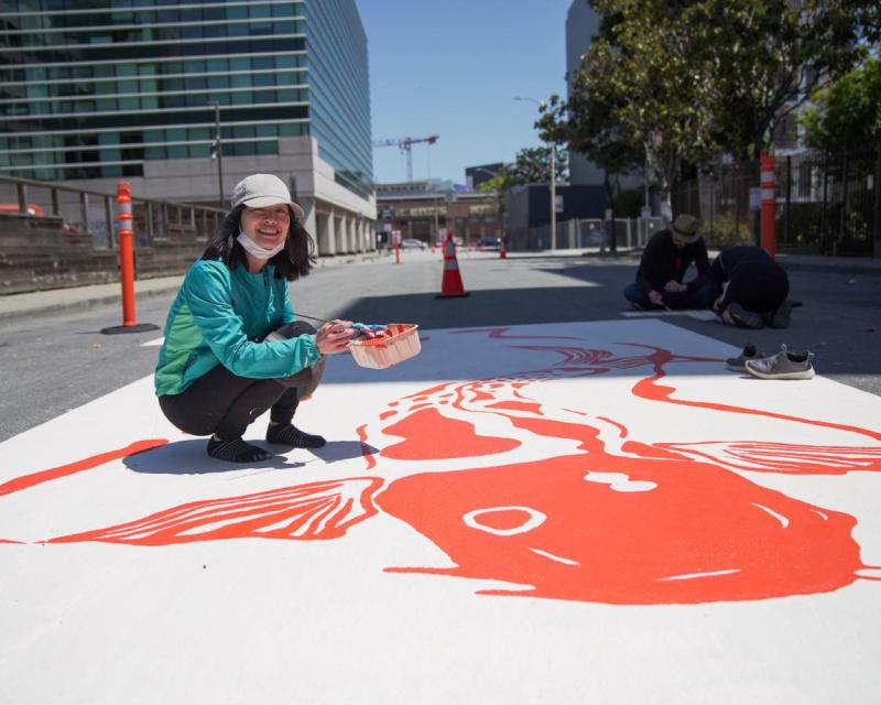 Photo of a community member painting a street mural on a SoMa Slow Street. Photo credit: Erina Alejo