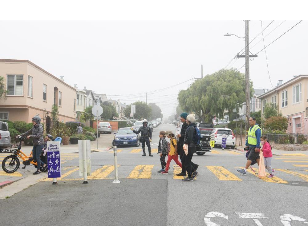 Kids cross Slow Hearst on their way to school.