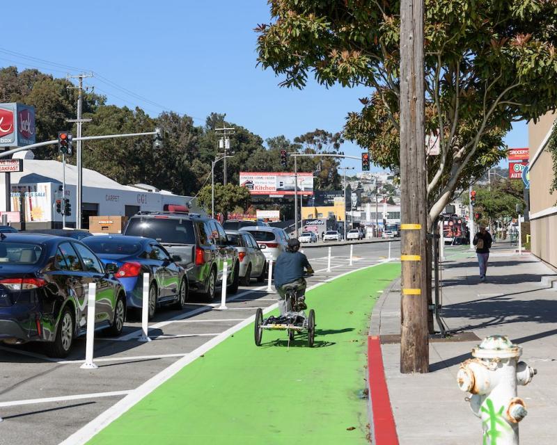 Biker with trailer riding in green painted, parking protected, bike lane 