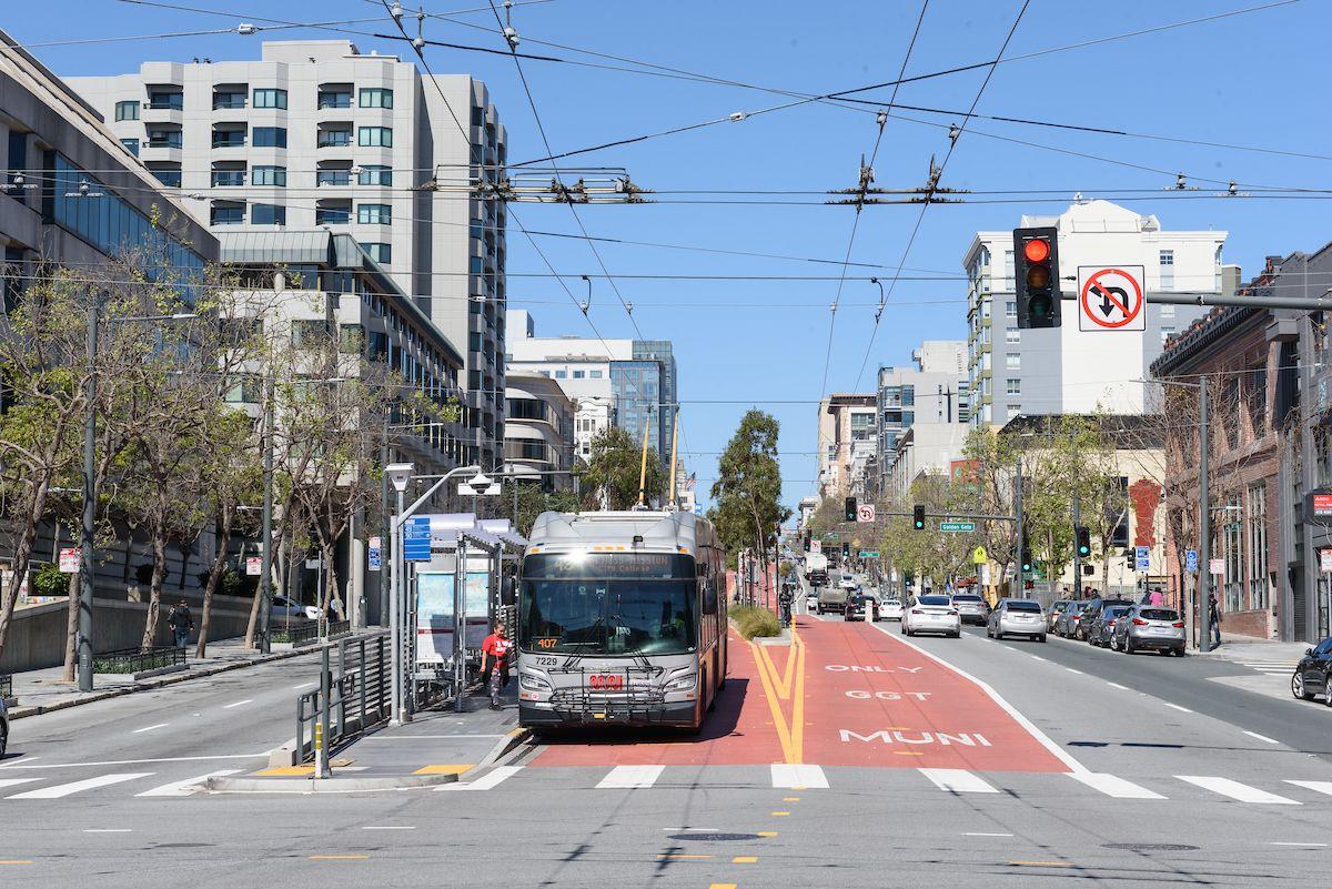 49 Van Ness bus stops at a boarding island on Van Ness Avenue, using one of its red, transit-only lanes.