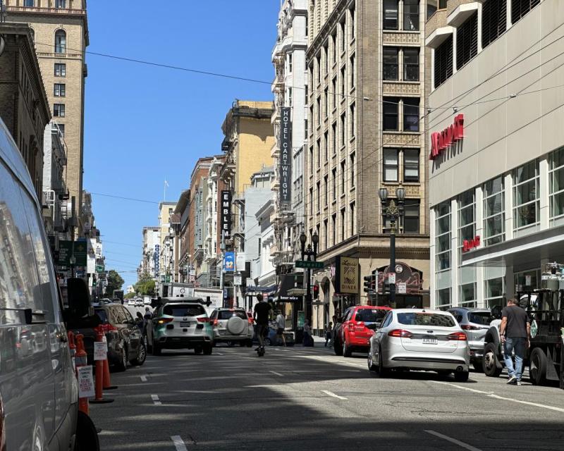 Vehicles and scooter traffic traveling west on Sutter Street, vehicle double parking