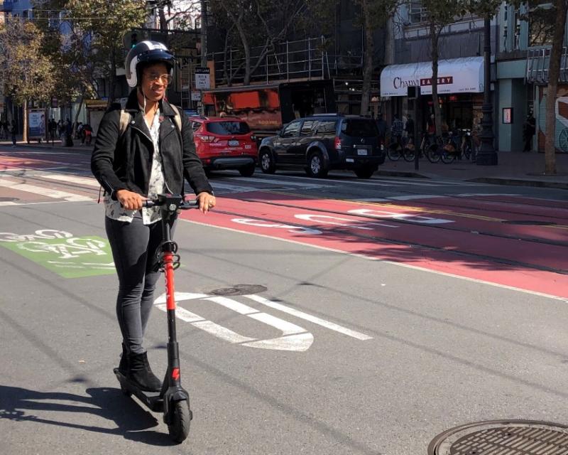 Lady on scooter riding with helmet.