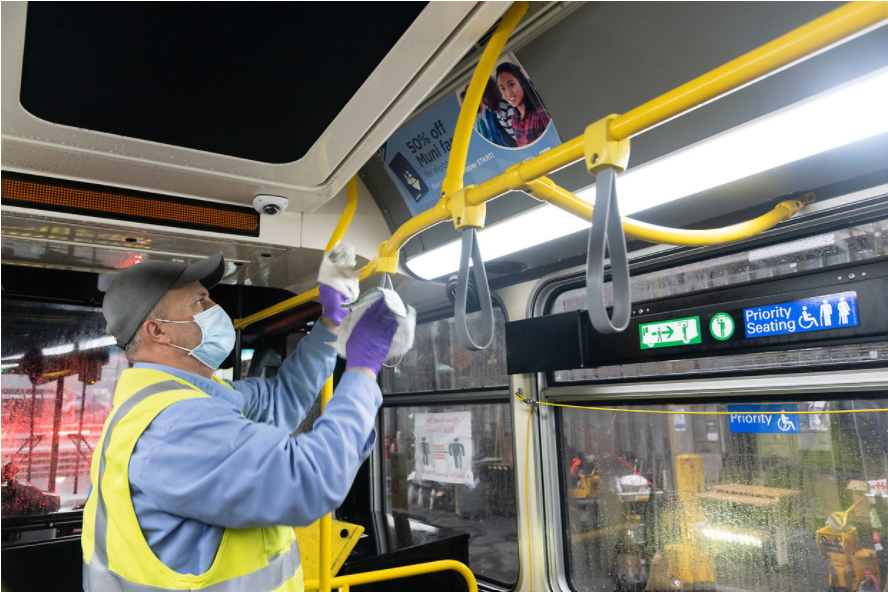 Muni employee wiping down a Muni vehicle to sanitize it